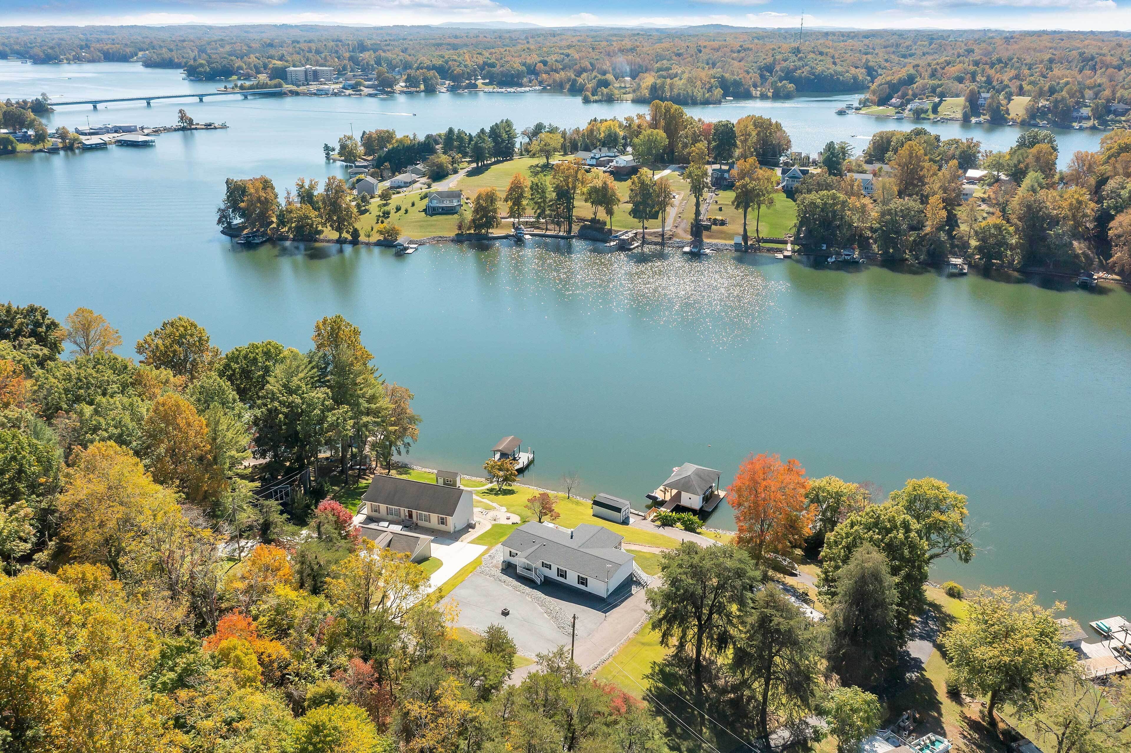 A residential area with houses near a lake, a bridge in the distance, and a mix of trees and open spaces.