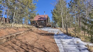A dirt path leading to a wooden cabin with a red roof, surrounded by trees and a clear blue sky. - Divide Cabin in the Heart of Colorful Colorado! (Divide)