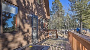 A wooden cabin with a stone patio, a deck, and a view of the surrounding forest. - Divide Cabin in the Heart of Colorful Colorado! (Divide)