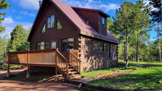 A log cabin with a wooden deck, a staircase, and a red roof. - Divide Cabin in the Heart of Colorful Colorado! (Divide)