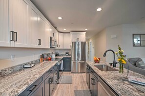 Una cocina moderna con armarios blancos, electrodomésticos de acero inoxidable y encimeras de granito.