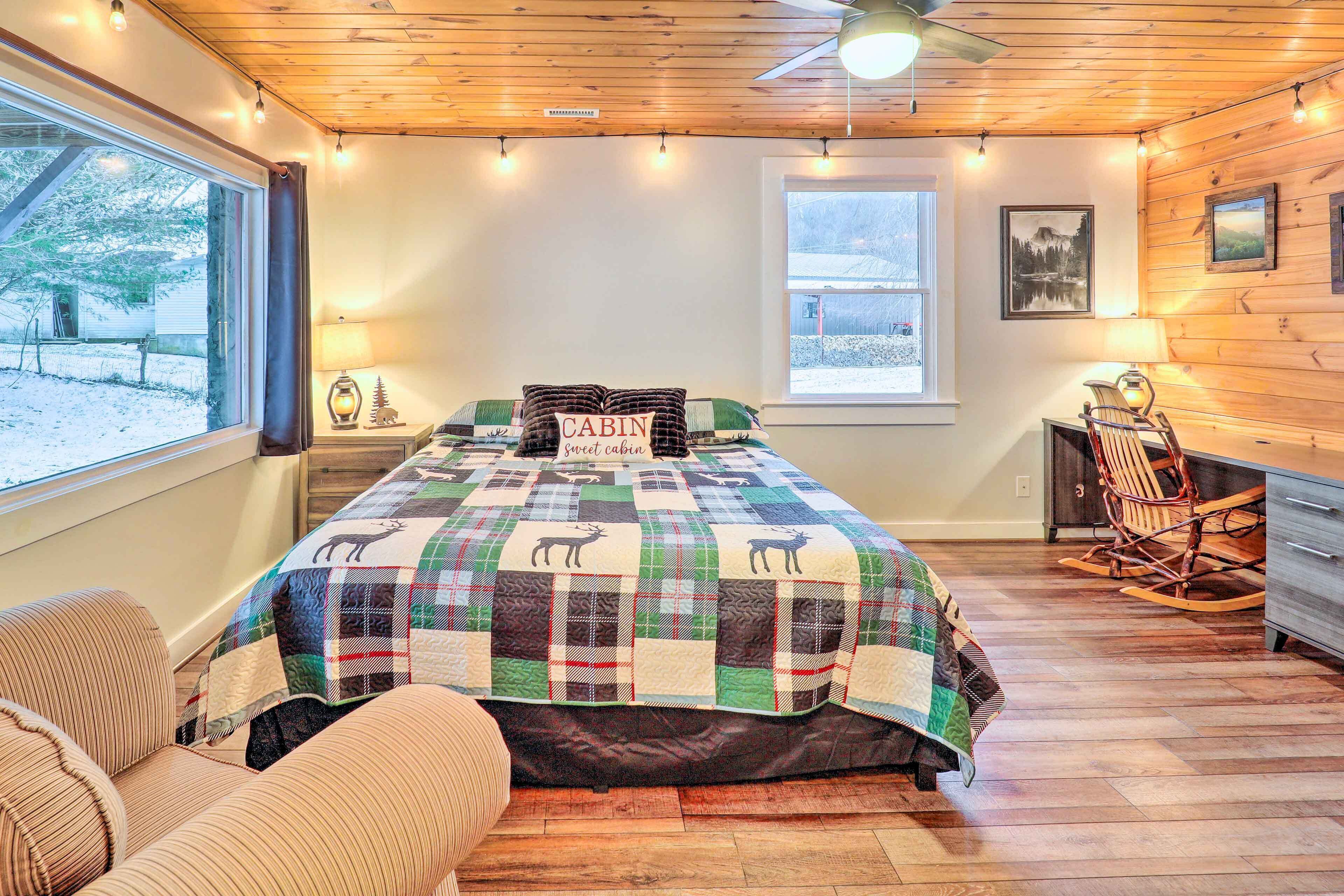 A cozy cabin-style bedroom with a large bed, a rocking chair, and a view of the snowy outdoors.