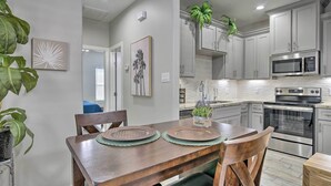 A modern kitchen with grey cabinets, stainless steel appliances, and a dining area with a wooden table and chairs. - Private Patio: Edinburg Couple's Retreat! (Edinburg)