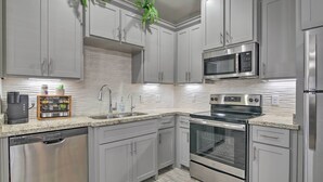 A modern kitchen with grey cabinets, stainless steel appliances, and a granite countertop. - Private Patio: Edinburg Couple's Retreat! (Edinburg)