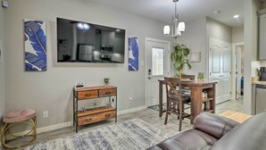 A modern living room with a leather sofa, a dining area with a wooden table and chairs, and a kitchen in the background. - Private Patio: Edinburg Couple's Retreat! (Edinburg)