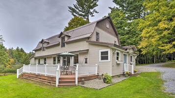 A two-story house with a covered porch, a deck, and a gravel driveway.