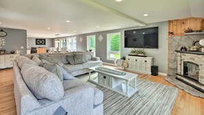 Een moderne woonkamer met een grijze bank, een witte salontafel en een stenen open haard.
