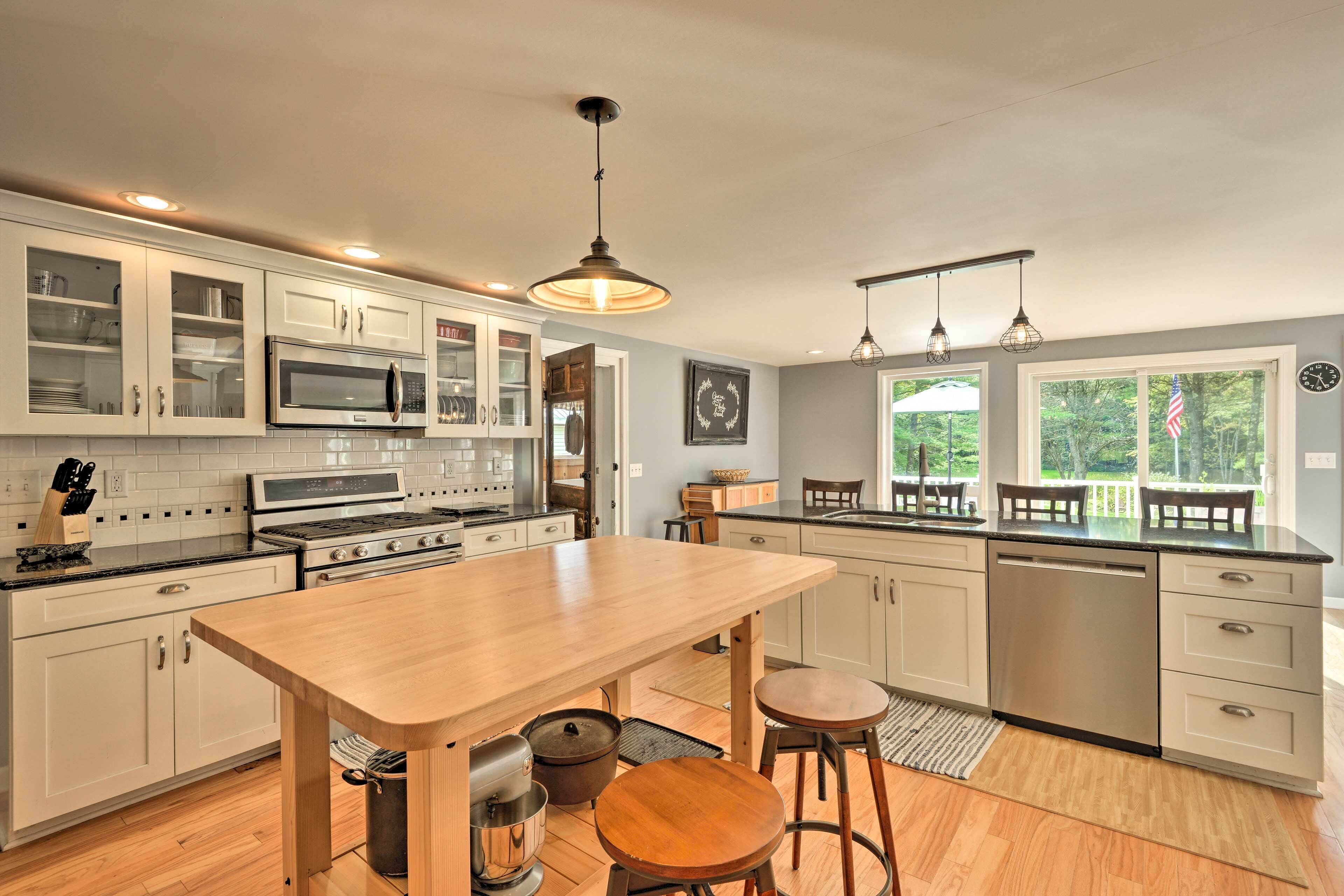 A modern kitchen with white cabinets, stainless steel appliances, and a wooden island.