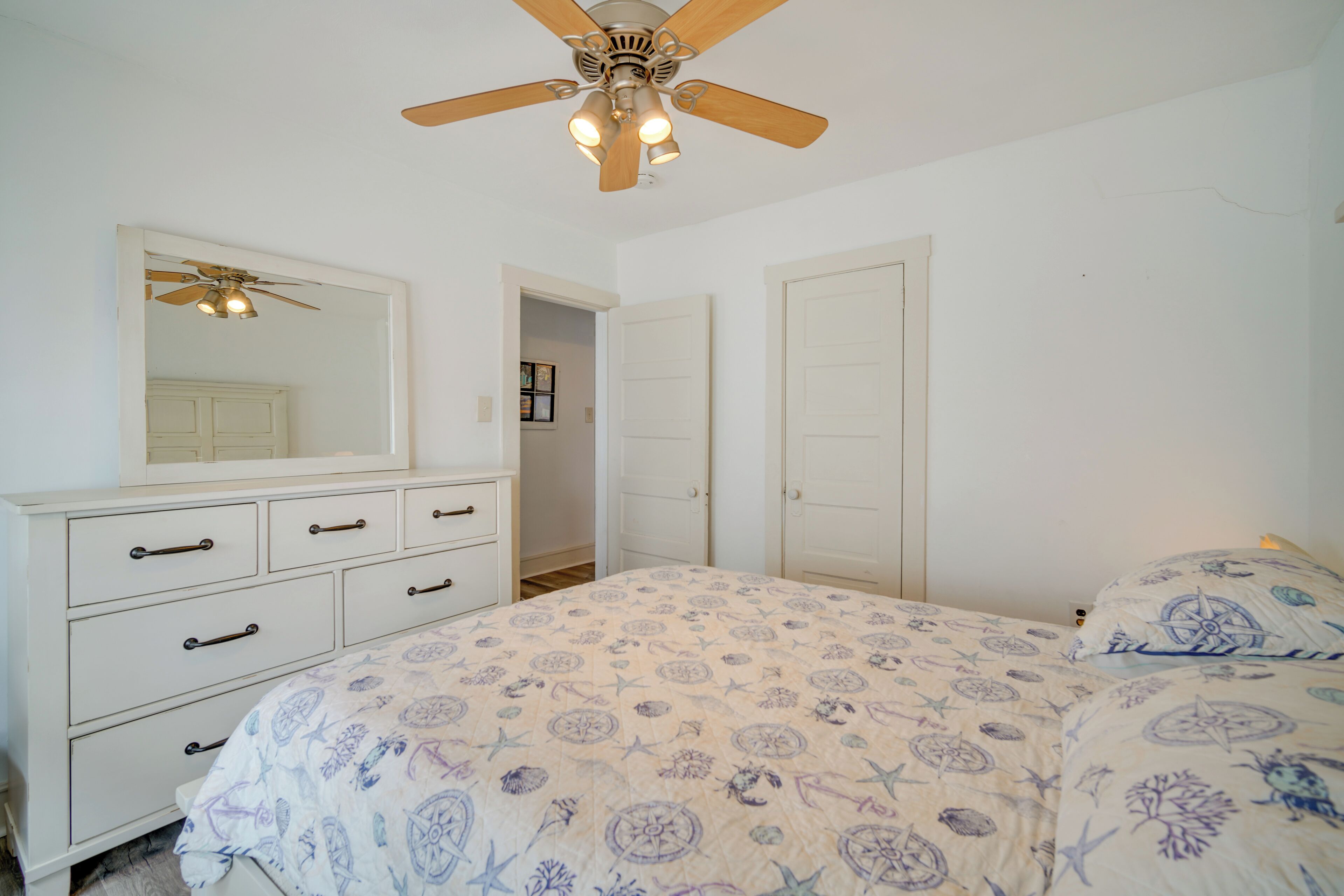 Ein Schlafzimmer mit Bett, Kommode und Deckenventilator.