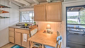 A compact kitchen with wooden cabinets, a sink, and a table with chairs. - Newfound Lake Studio: Bbq, Fire Pit & Beach Access (Bristol)