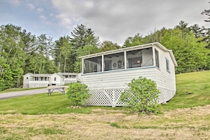 A white mobile home with a covered porch, surrounded by a grassy area and trees. - Newfound Lake Studio: Bbq, Fire Pit & Beach Access (Bristol)