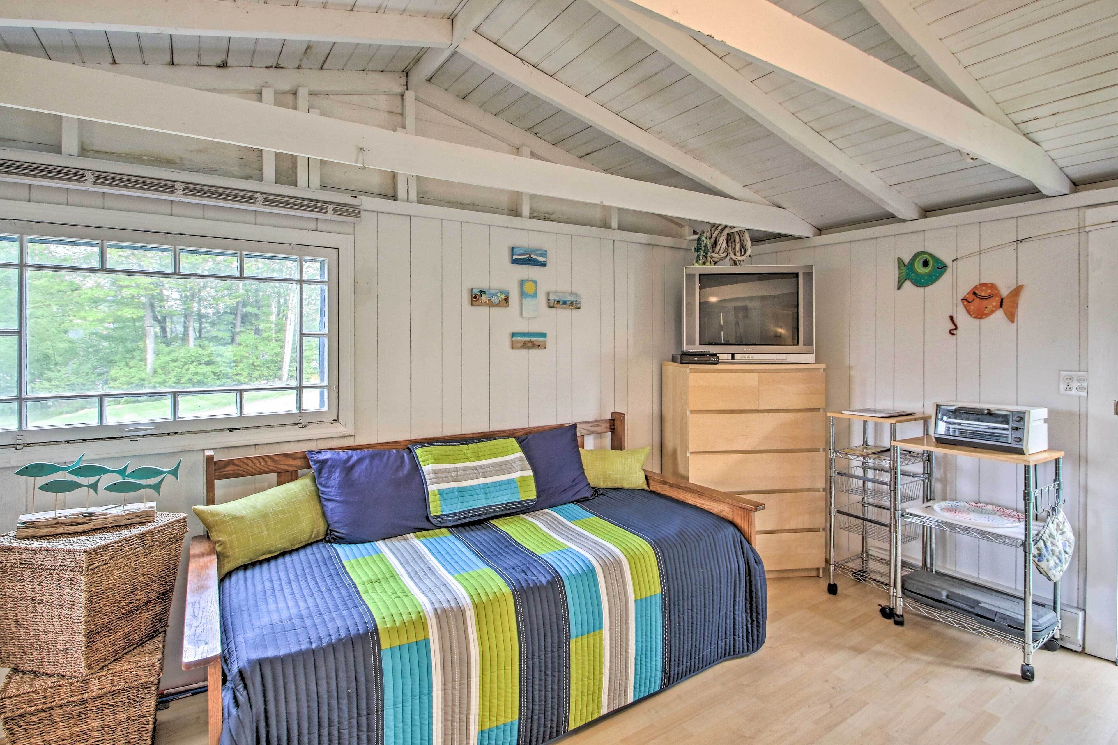 Quarto com cama, televisão, armário de madeira e carrinho de metal.
