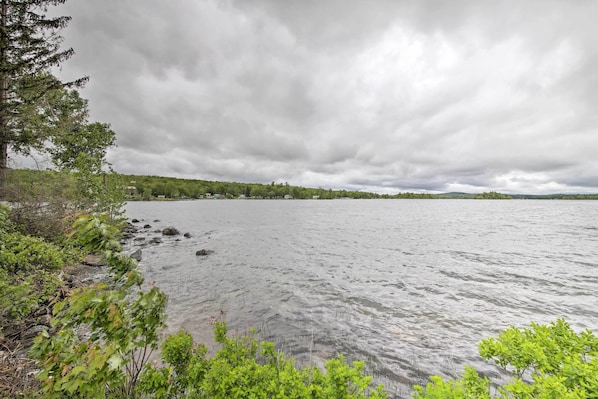 A calm lake with a rocky shoreline and dense greenery. - Pet-friendly Togus Pond Home: Kayak & Canoe! (Augusta)