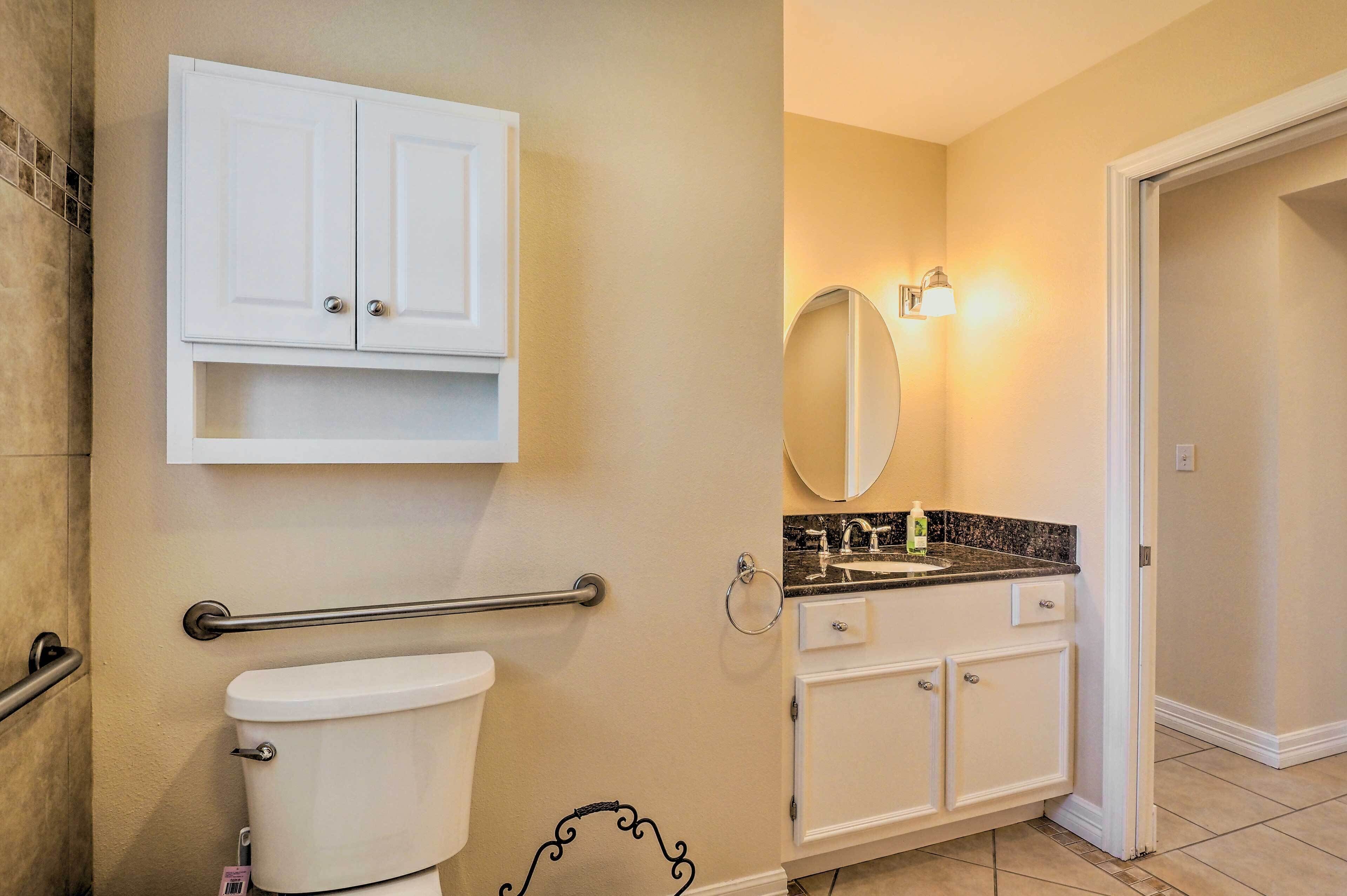 A bathroom with a toilet, a vanity with a sink, a mirror, and a towel rack.