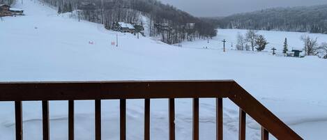 A snowy mountain landscape with a wooden deck in the foreground.