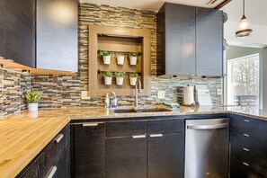 Een moderne keuken met donkere kastjes, een betegelde spatwand en een ingebouwde vaatwasser.