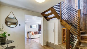 Un intérieur moderne comprenant un escalier, un grand miroir rond, un coin repas avec une table et des chaises, et un salon avec un canapé et une cheminée.