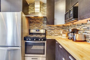 Een moderne keuken met roestvrijstalen apparatuur, een betegelde spatwand en houten aanrechtbladen.