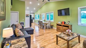 A spacious living room with a dark-colored sofa, a coffee table, and a dining area with a table and chairs.