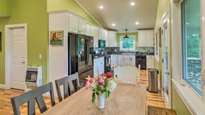 A modern kitchen with white cabinets, a dining table with chairs, and a vase of flowers.