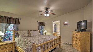 A bedroom with a wooden bed, a ceiling fan, a dresser, and a television. - 'red Rock Rambler' Moab Home w/ Hot Tub & Views! (Moab)