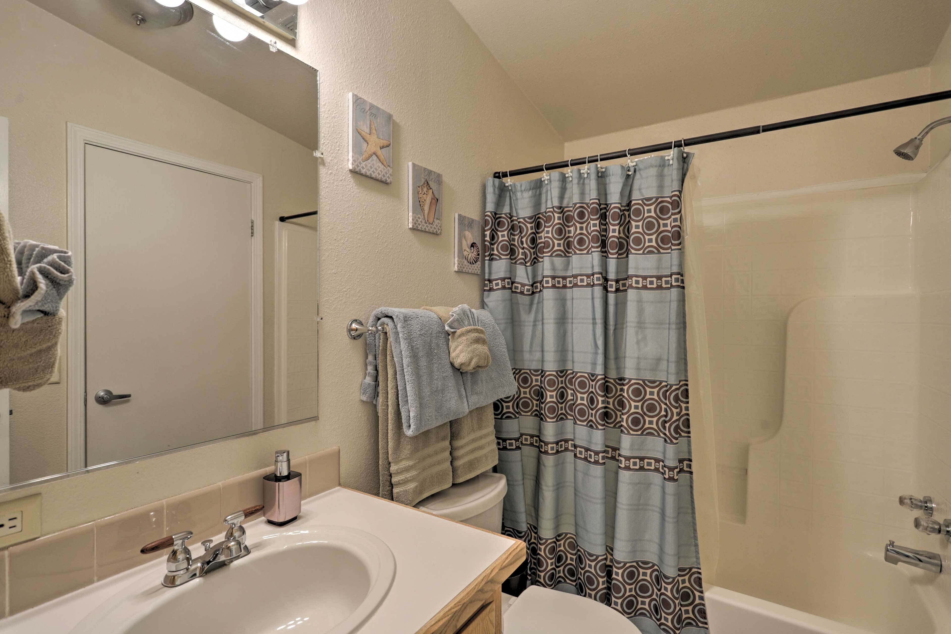 Un baño con lavamanos, espejo, inodoro y cortina de ducha.