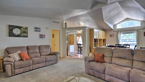A living room with two brown sofas, a glass coffee table, and a clock on the wall. - 'red Rock Rambler' Moab Home w/ Hot Tub & Views! (Moab)