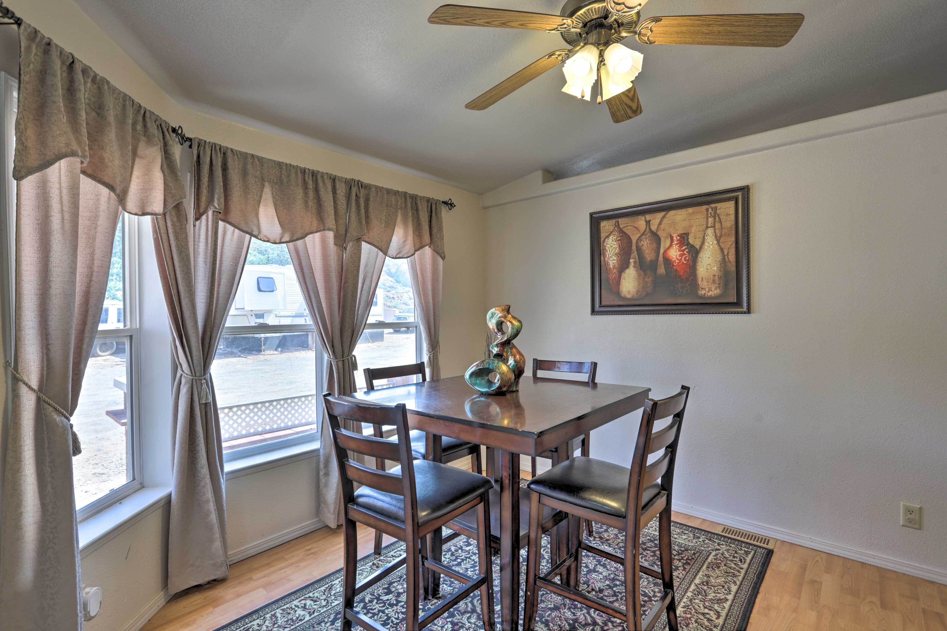A dining area with a wooden table and chairs, a ceiling fan, and a window with curtains.