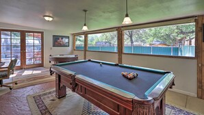 A pool table in a room with large windows, a chair, and a rug. - 'red Rock Rambler' Moab Home w/ Hot Tub & Views! (Moab)