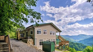 A two-story cabin with a stone foundation, a green metal roof, and a wooden deck. - Private Blue Ridge Home w/ Hot Tub, Mountain Views (Marshall)