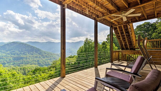 A wooden deck with two reclining chairs and a ceiling fan, overlooking a mountainous landscape. - Private Blue Ridge Home w/ Hot Tub, Mountain Views (Marshall)