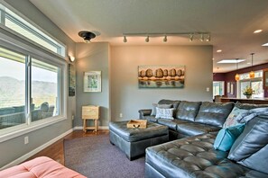 A modern living room with a large window, a dark leather sofa, and a painting on the wall. - Private Blue Ridge Home w/ Hot Tub, Mountain Views (Marshall)