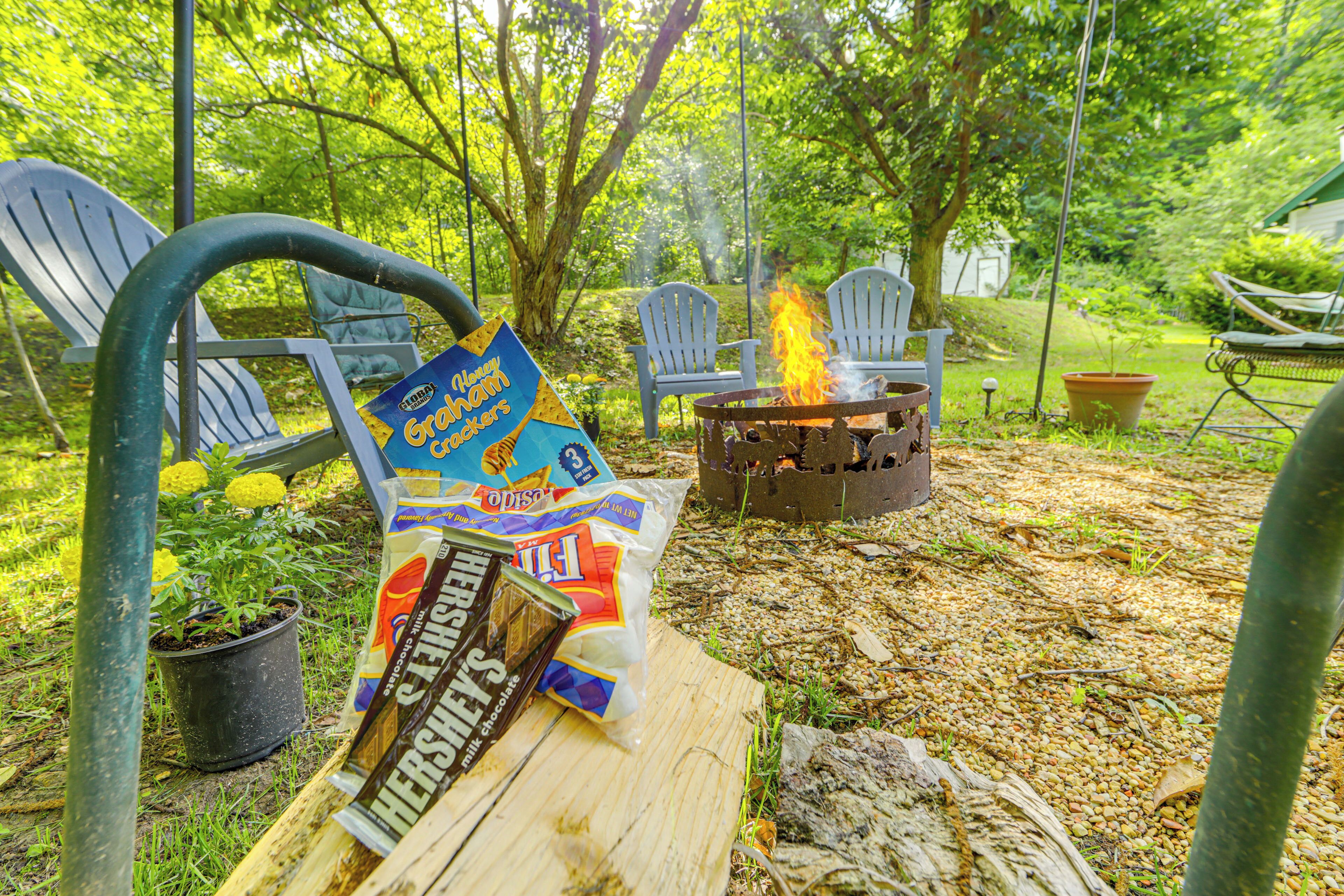 Ein Garten mit Feuerstelle, Gartenmöbeln und einem Holztisch mit Snacks.