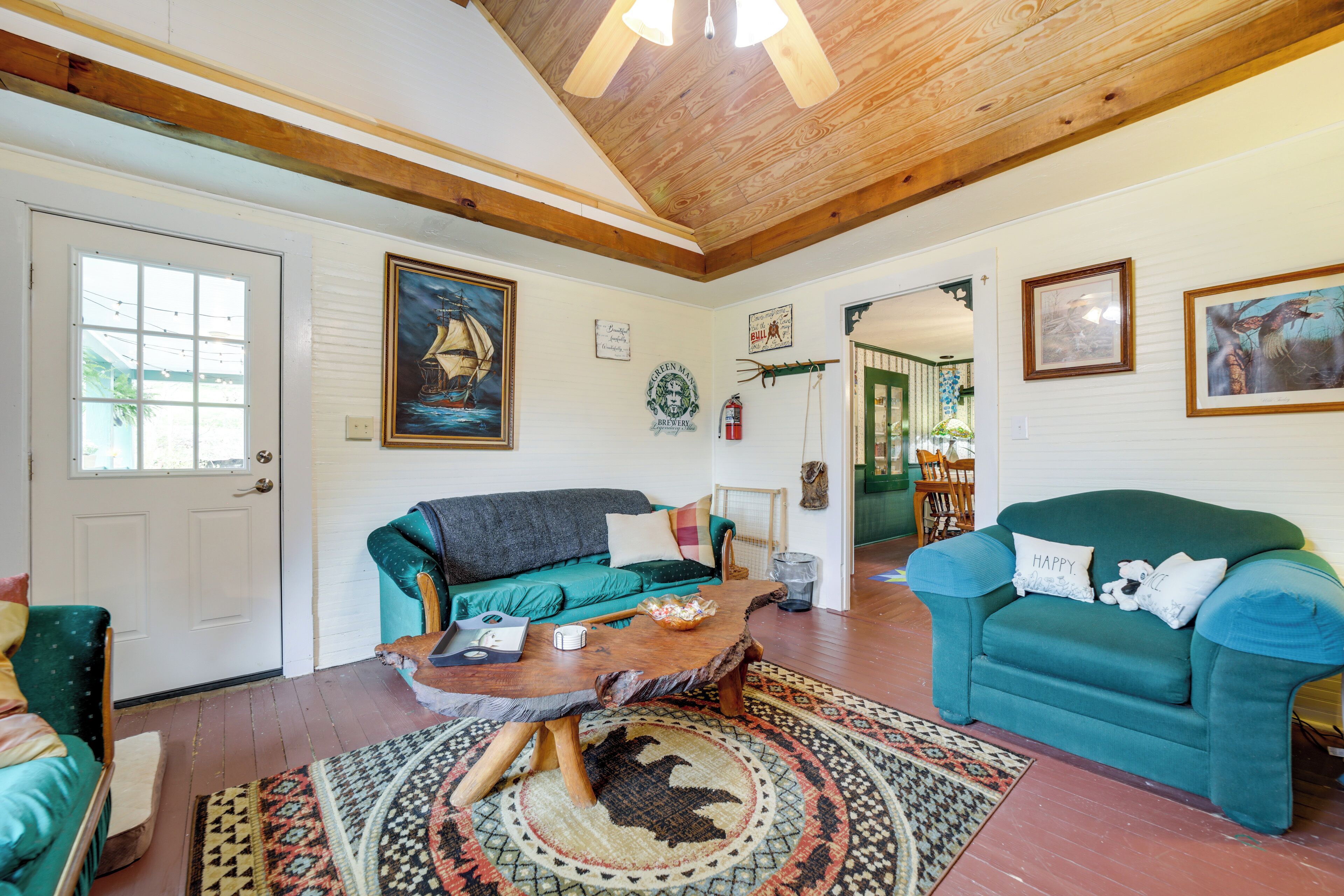Un salon chaleureux avec un plafond en bois, des canapés de couleur turquoise, une table basse et un tapis à motifs.