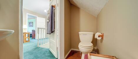 A bathroom with a toilet, a framed sign, and a candle.
