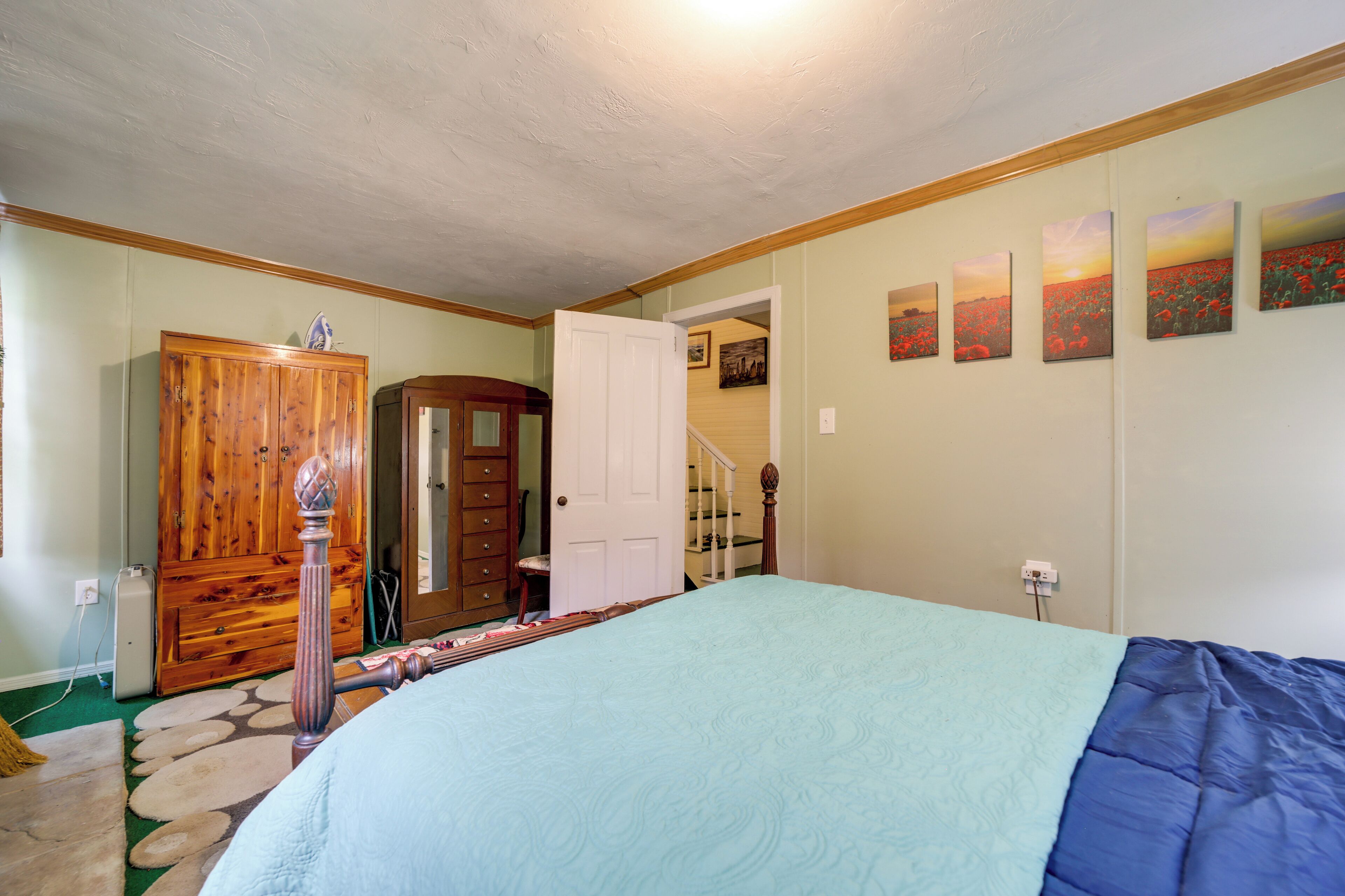 Un dormitorio con cama, un armario de madera, una puerta y una escalera.
