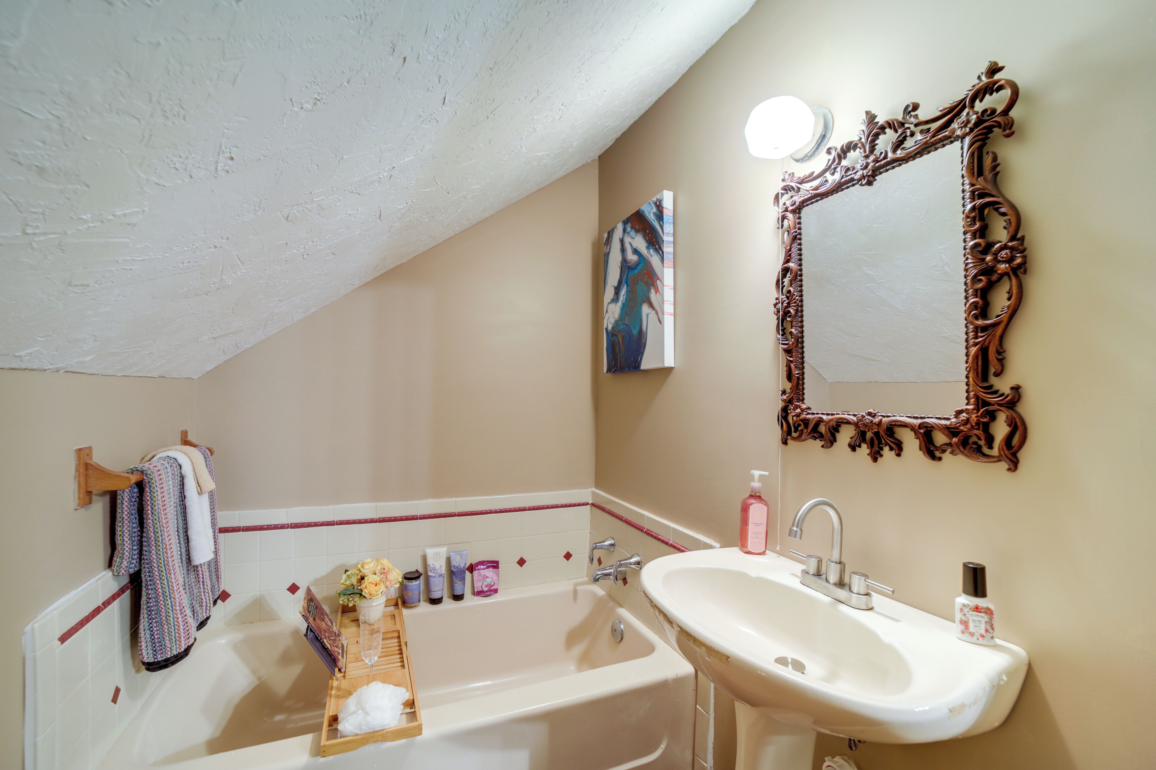 Une salle de bain équipée d’une baignoire, d’un lavabo, d’un miroir décoratif et d’un porte-serviettes avec des serviettes à motifs.