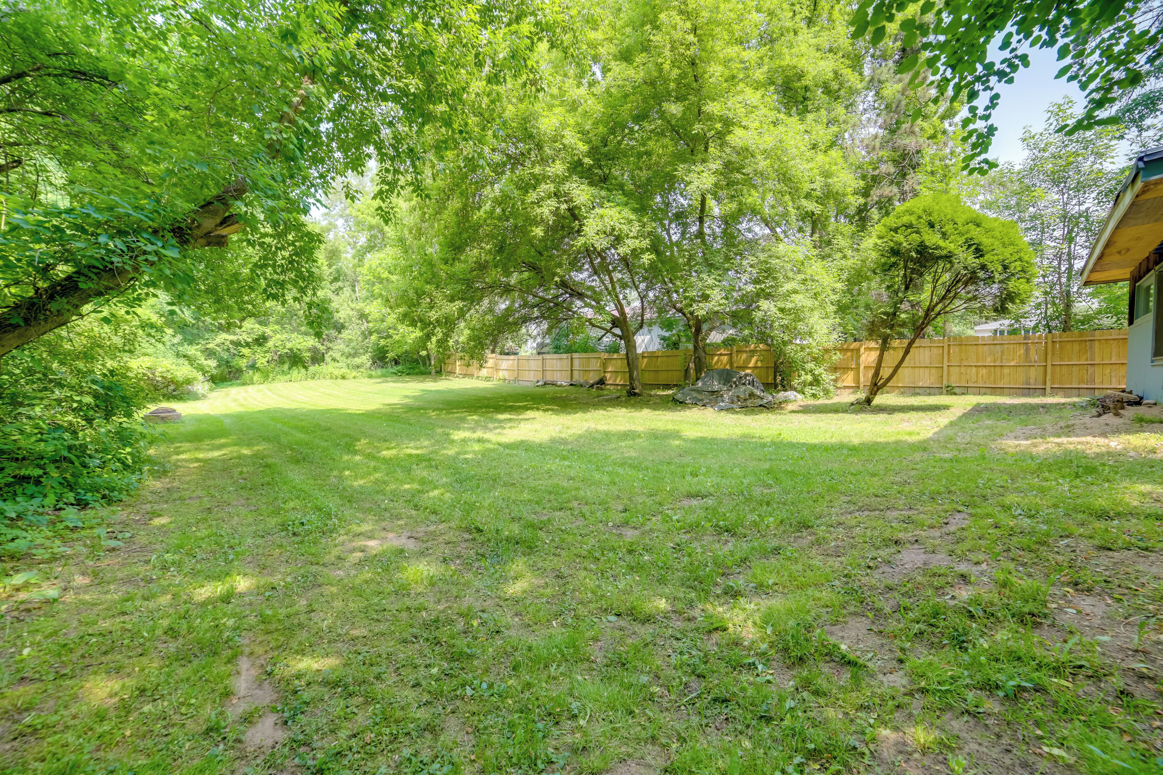 A well-maintained backyard with a lawn, trees, and a wooden fence.