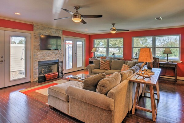 A spacious living room with a fireplace, a large sofa, a coffee table, and a TV mounted on the wall.