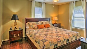 A bedroom with a large bed, two bedside tables, a ceiling fan, and a window with curtains. - Pottsboro Home on 2 Acres w/ Hot Tub, Near Marina! (Pottsboro)