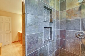 Baño con baldosas de piedra, zona de ducha y una puerta.