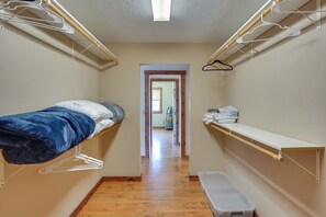 A narrow hallway with a bed on the left, a bench on the right, and a shelf with folded clothes.