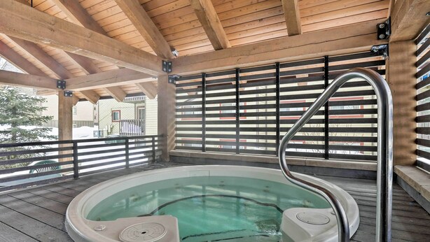 Ein Whirlpool unter einer Holz-Pergola mit Metallgeländern.