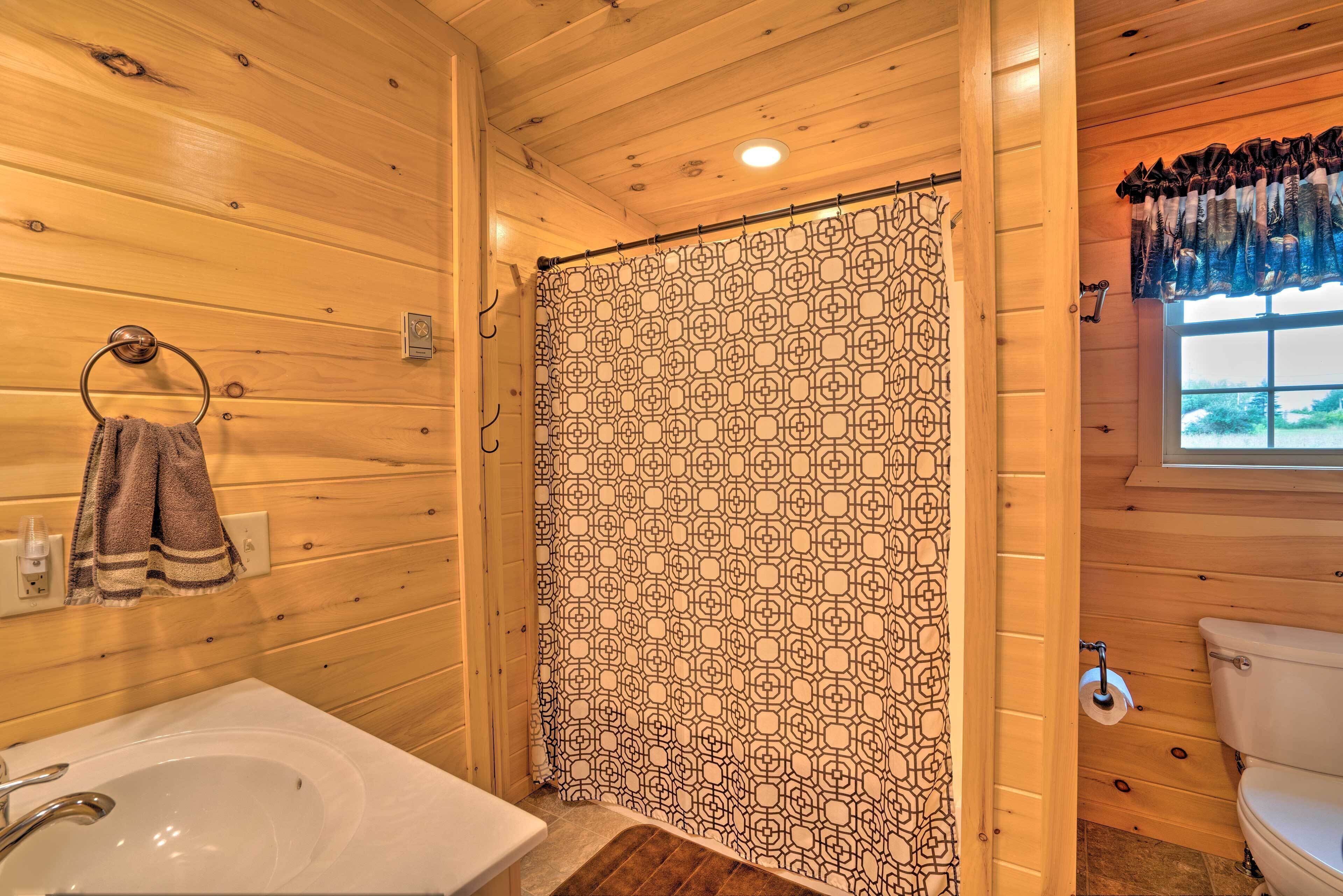 Un baño de cabaña de madera con bañera, inodoro y lavamanos.