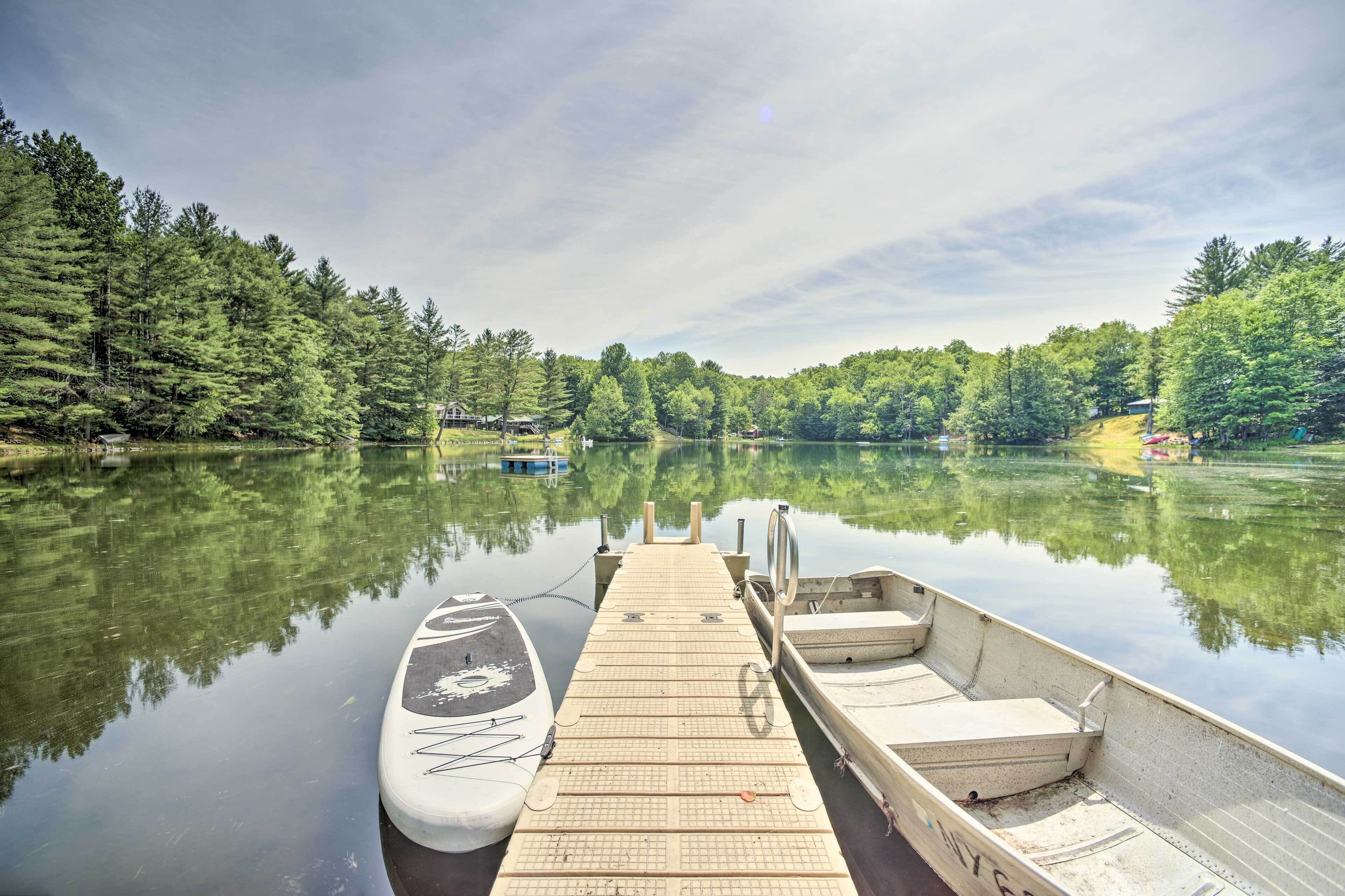 A wooden dock extending into calm water with boats docked, surrounded by dense forest.