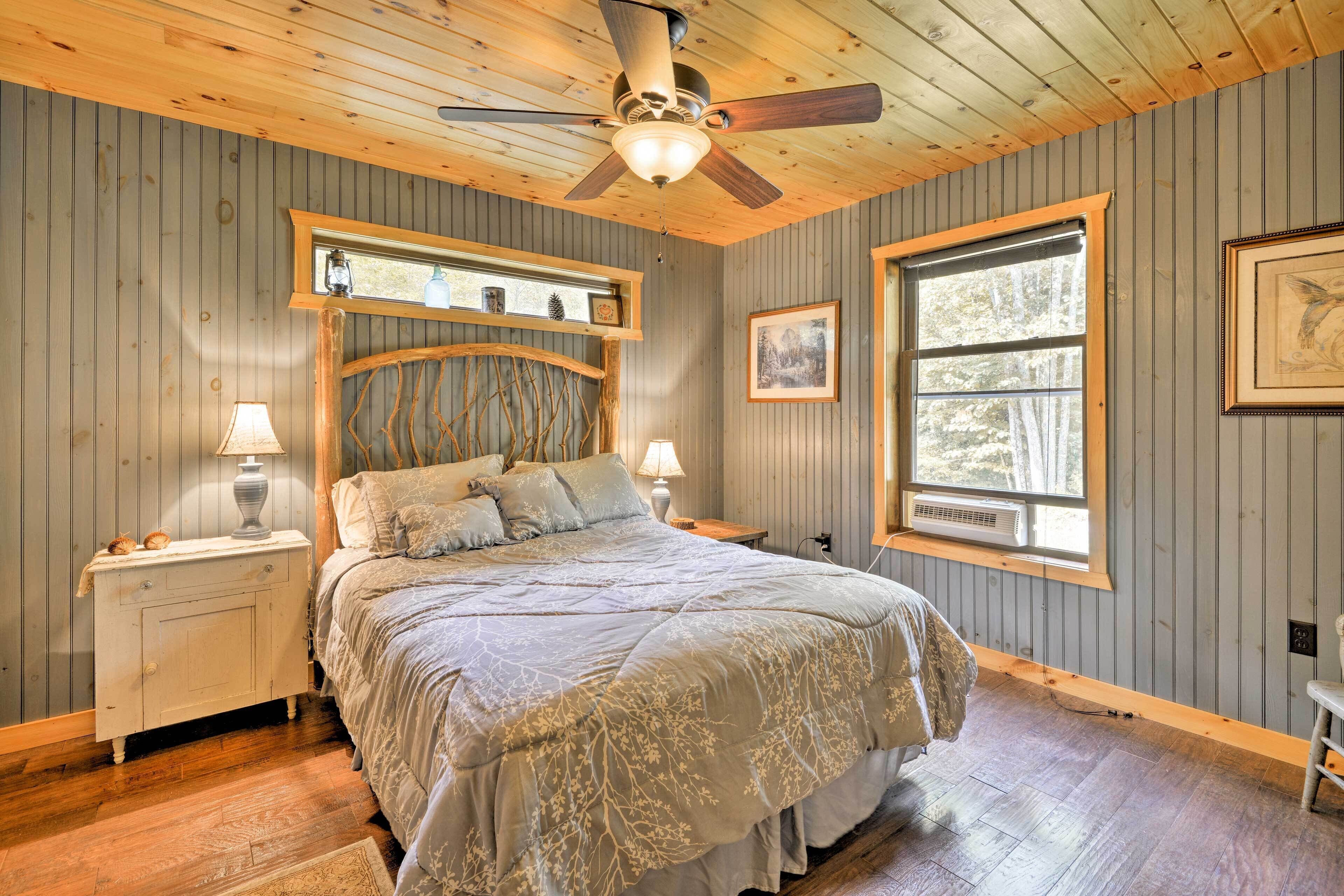 Ein Schlafzimmer mit einem Bett, einem Holzkopfende, zwei Nachttischen, einem Deckenventilator und einem Fenster.