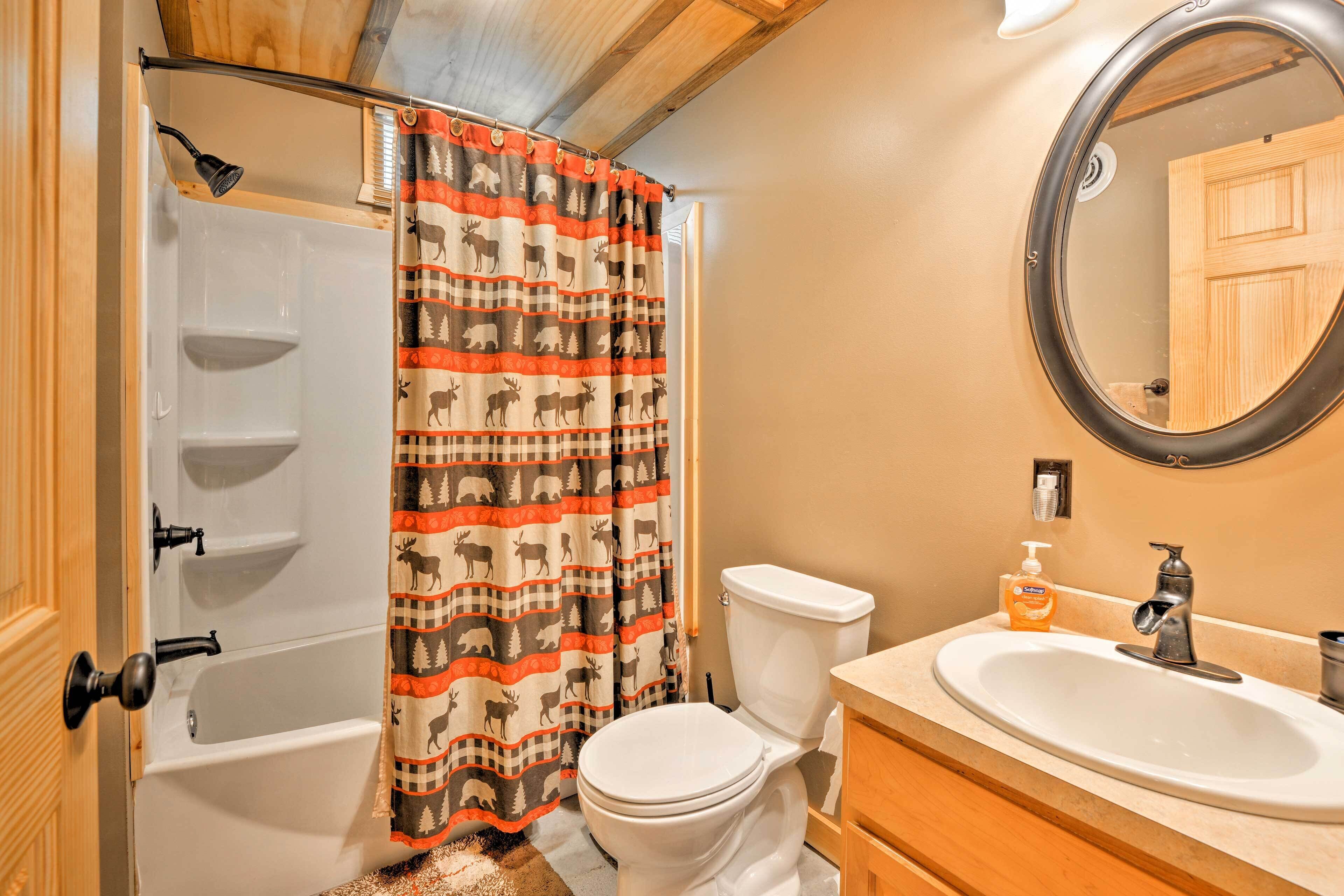 A bathroom with a shower, toilet, sink, and a mirror.