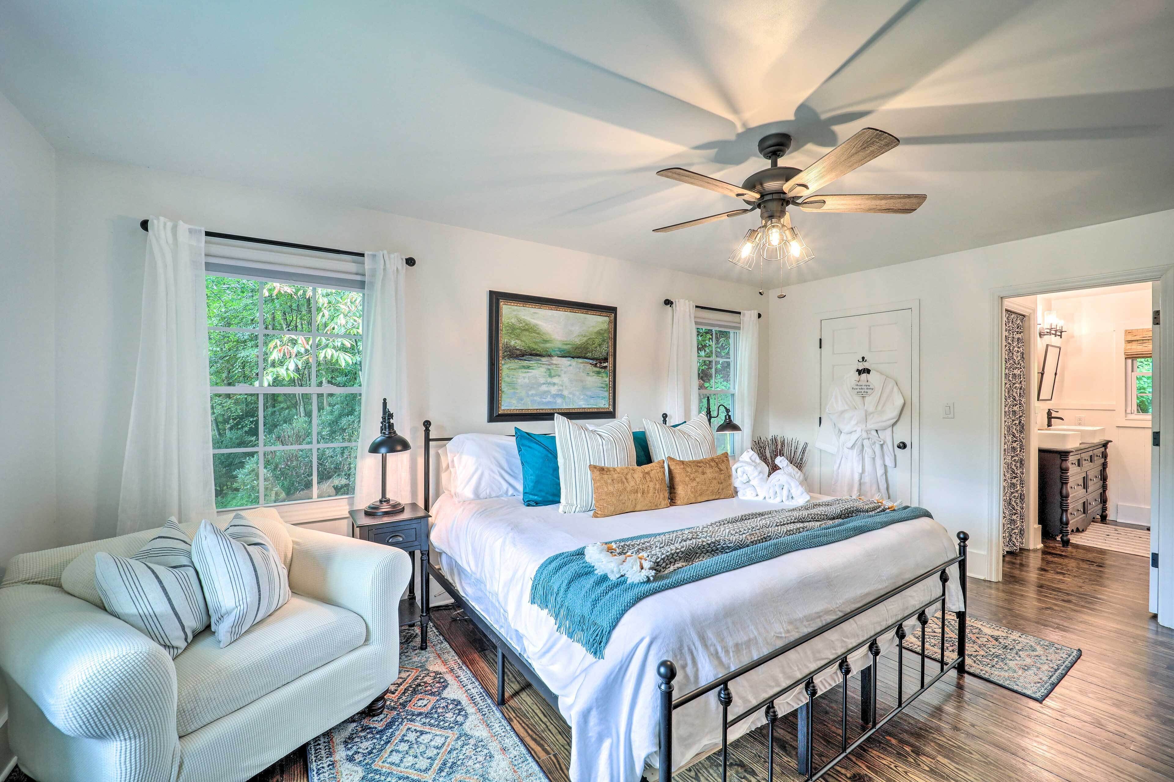 A bedroom with a large bed, a bedside table, a chair, and a ceiling fan.