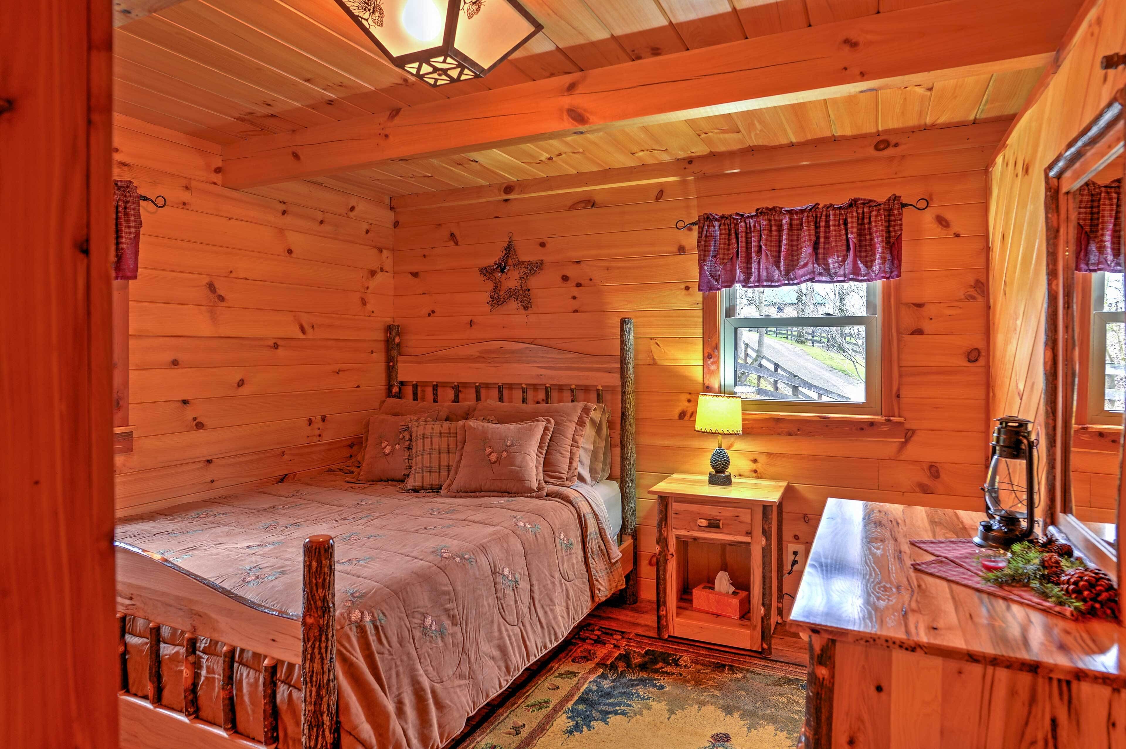 A cozy wooden cabin bedroom with a bed, a nightstand, a lamp, and a window with curtains.