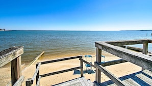 A wooden pier leading to a sandy beach with a clear blue sky. - Refreshing Colonial Beach Vacation Rental! (Colonial Beach)